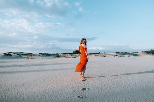 elegante mujer posando en la playa con vestido rojo