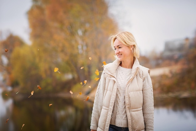 Elegante mujer rubia caminando y relajándose al aire libre en otoño