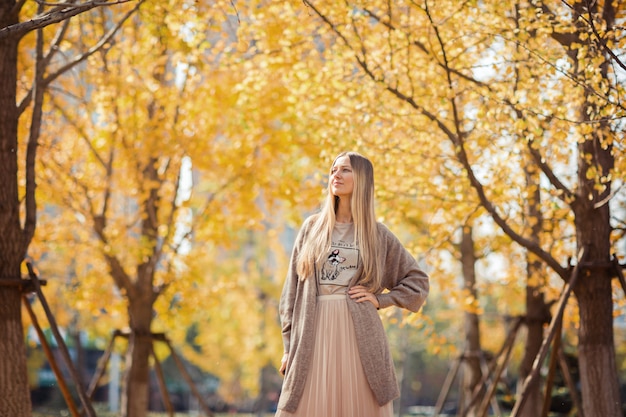 Elegante mujer rubia en parque otoñal