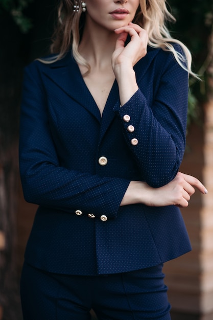 Elegante mujer rubia en traje azul oscuro con botones dorados