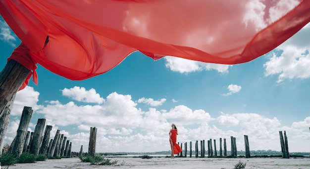 Elegante mujer rubia con vestido rojo en la playa