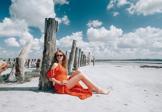 Elegante mujer rubia con vestido rojo en la playa