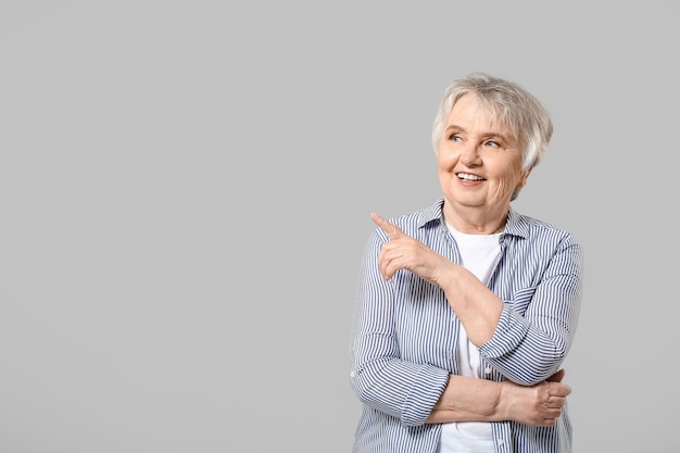 Elegante mujer senior en pared gris