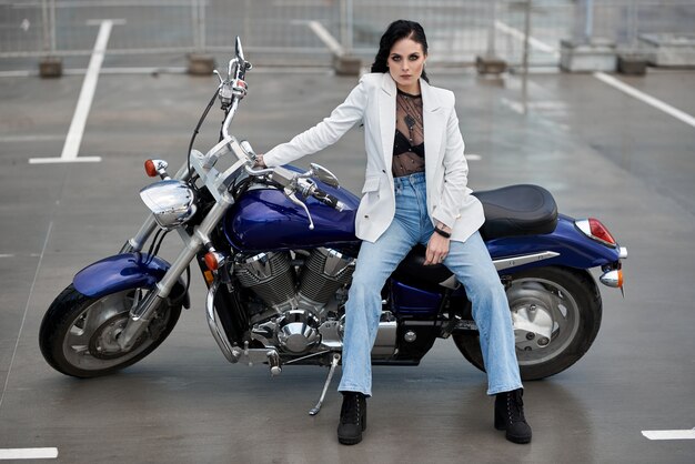 Elegante mujer sentada en una motocicleta estacionada cerca de un centro comercial.