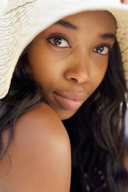 Elegante mulher afro-americana com cabelo comprido e chapéu de sol