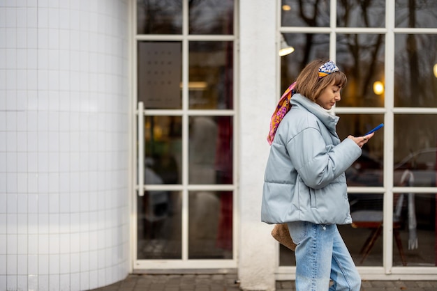 Elegante mulher caminha com telefone ao ar livre