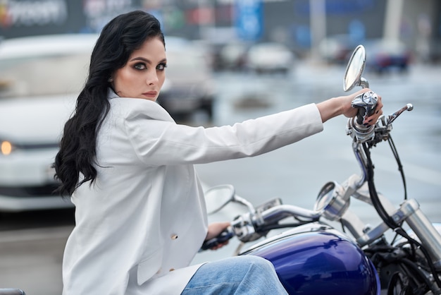 elegante mulher sentada em uma motocicleta estacionada perto de um shopping center.