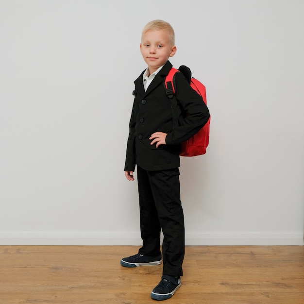 Elegante niño de moda en un traje con una mochila escolar.