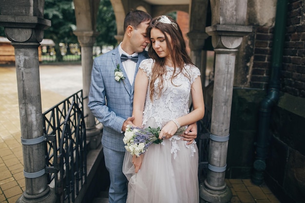 Elegante noiva e noivo abraçando no fundo da velha igreja Momento romântico Casamento na Provence Lindo casal de noivos sensuais abraçando-se suavemente na cidade europeia