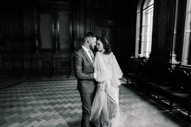 Elegante novia hermosa y elegante novio en una increíble habitación antigua y rica. Concepto de boda de lujo