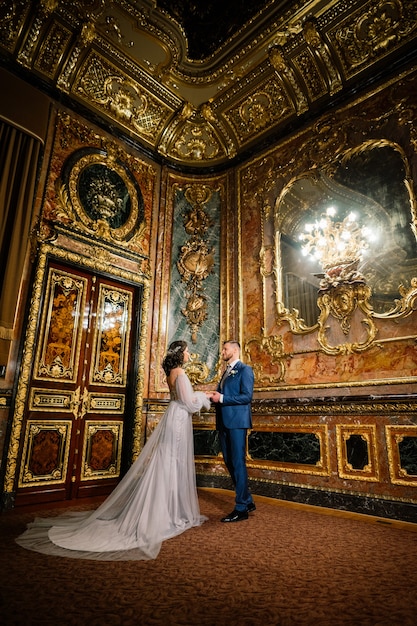 Elegante novia hermosa y elegante novio en una increíble habitación antigua y rica. Concepto de boda de lujo