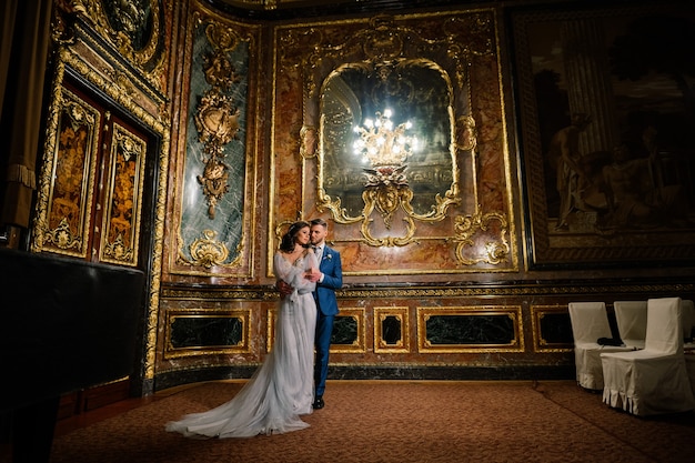 Elegante novia hermosa y elegante novio en una increíble habitación antigua y rica. Concepto de boda de lujo