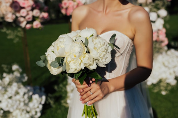 Elegante novia con hermoso ramo de novia tierno de peonías frescas