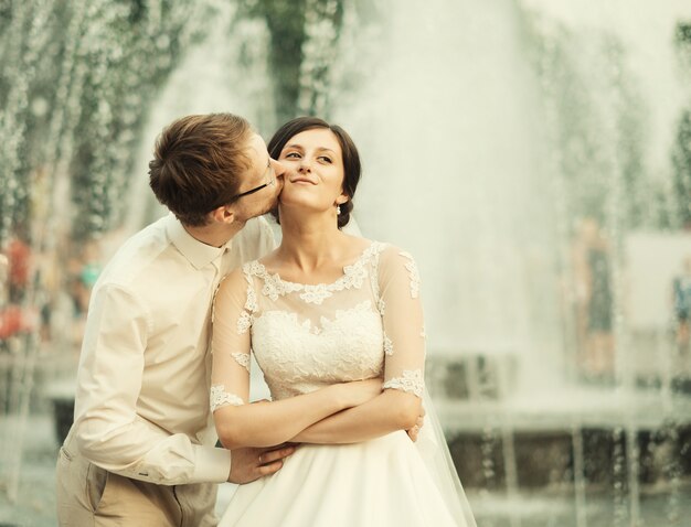 Elegante novia de lujo y elegante novio, abrazándose con ternura, en el espacio de la ciudad vieja de Lviv