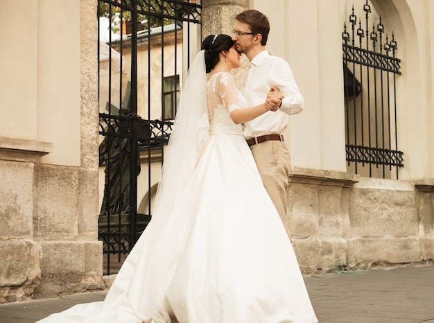 Elegante novia de lujo y elegante novio, abrazándose con ternura, en el fondo de la ciudad vieja de Lviv