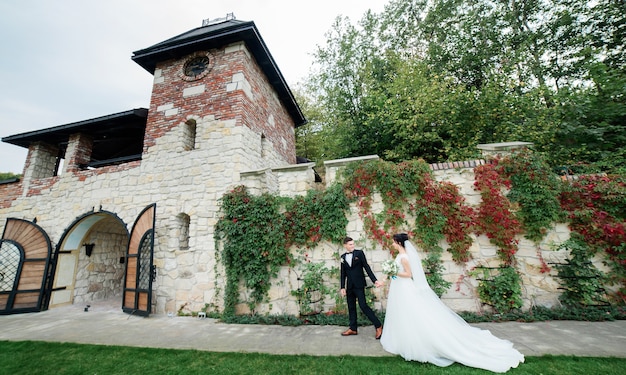 Elegante novia y el novio en traje negro y zapatos marrones caminar afuera