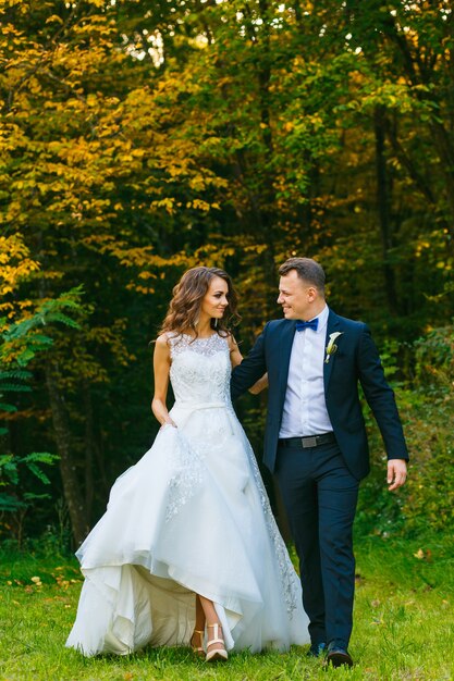 Elegante novia rizada y elegante novio caminando en el hermoso parque de verano