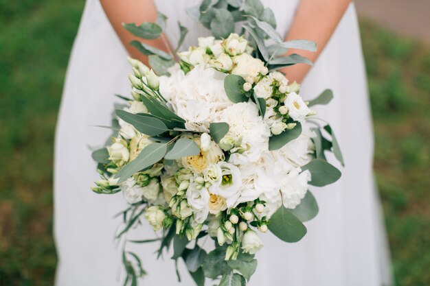 Elegante novia en vestido de novia blanco con hermoso ramo