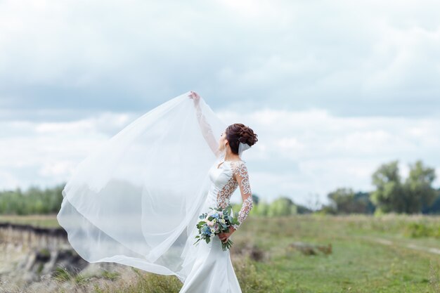 Elegante novia en un vestido de novia con encaje con ramo de flores de novia