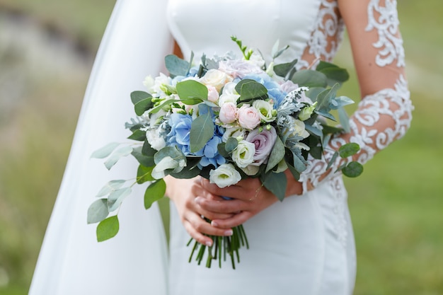 Elegante novia en un vestido de novia con encaje con ramo de flores de novia