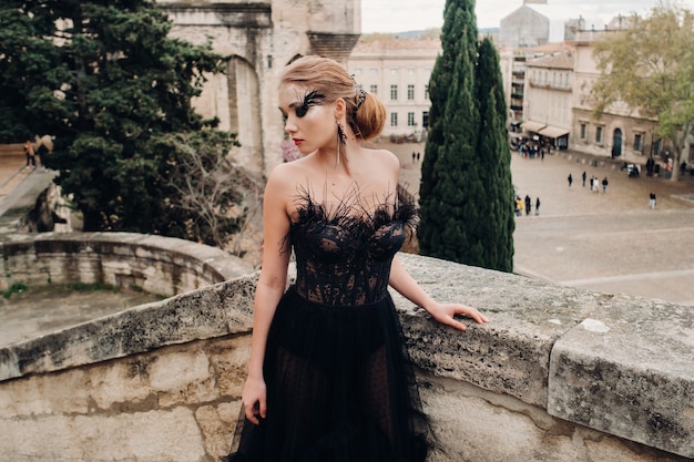 Una elegante novia con un vestido de novia negro posa en la antigua ciudad francesa de Aviñón. Modelo con un hermoso vestido negro. Sesión de fotos en la Provenza.