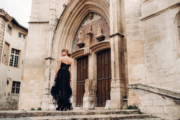 Una elegante novia con un vestido de novia negro posa en la antigua ciudad francesa de Aviñón