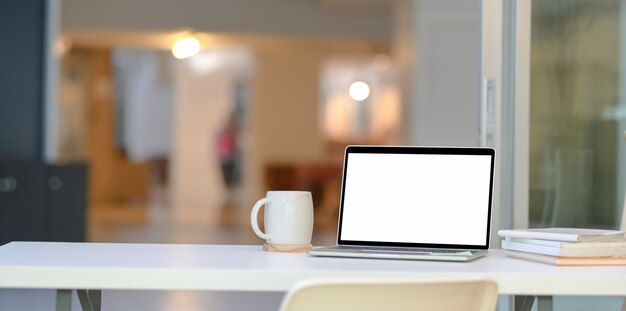 Elegante oficina en casa con computadora portátil con pantalla en blanco abierta