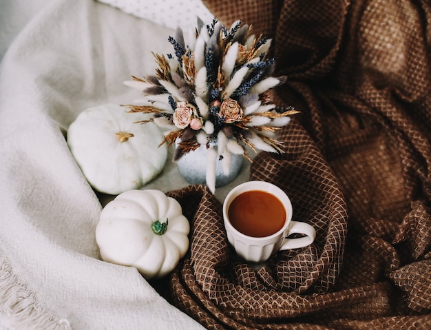 elegante outono plano deitado com uma xícara de café. flores e abóboras em um xadrez aconchegante