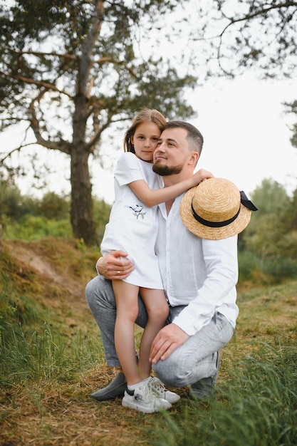 Elegante padre barbudo con su pequeña hija camina en el parque de verano