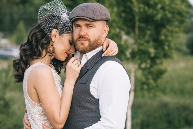 Elegante pareja de boda retro caminando en un campo cerca del lago