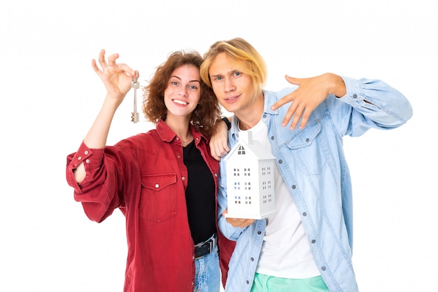 Elegante pareja caucásica en el amor compra una casa aislada en la pared blanca