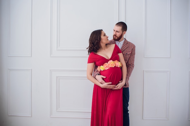 Elegante pareja embarazada. niña embarazada en vestido rojo