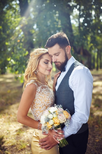 Elegante pareja de felices recién casados posando en el parque el día de su boda