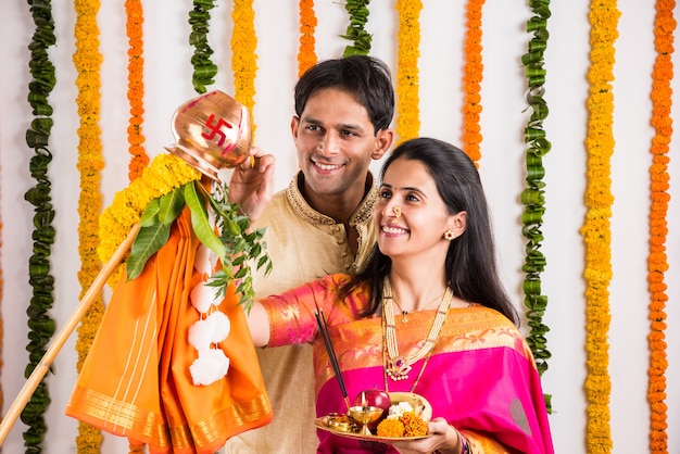 Elegante pareja de jóvenes indios realizando Gudi Padwa Puja con telas tradicionales y pooja thali. Es un año nuevo hindú celebrado en toda la India