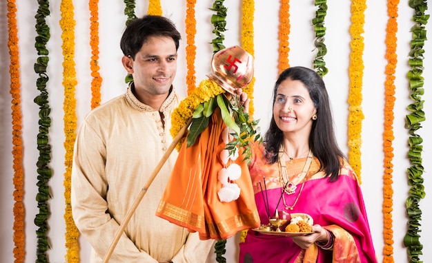 Elegante pareja de jóvenes indios realizando Gudi Padwa Puja con telas tradicionales y pooja thali. Es un año nuevo hindú celebrado en toda la India