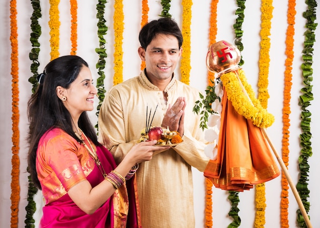 Elegante pareja de jóvenes indios realizando Gudi Padwa Puja con telas tradicionales y pooja thali. Es un año nuevo hindú celebrado en toda la India
