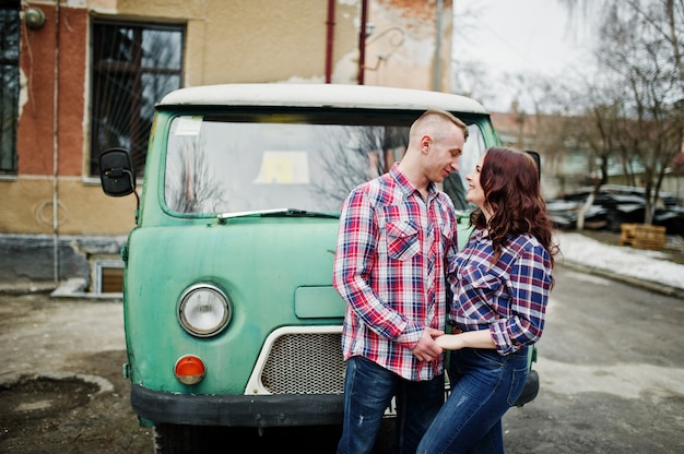 Elegante pareja usa camisa a cuadros en el amor juntos contra la vieja minivan