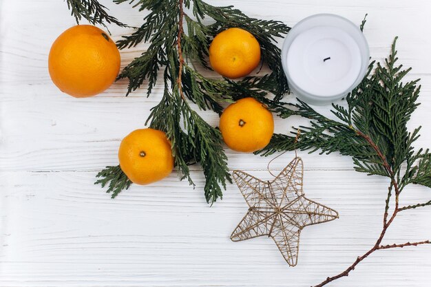 Foto elegante piso de navidad con ramas verdes y naranjas y estrella dorada sobre fondo blanco de madera rústica saludo de temporada y concepto de publicidad de compras texto espacial