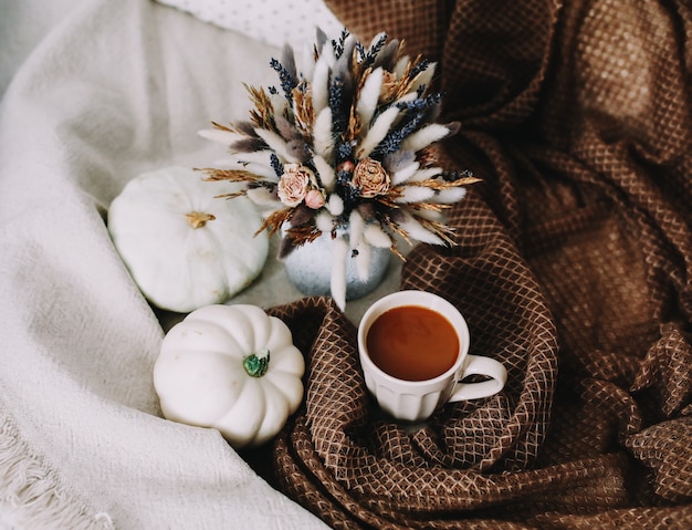 elegante piso de otoño con una taza de café. flores y calabazas en un acogedor plaid