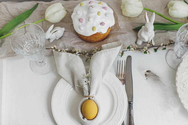 Elegante puesta de mesa de brunch de Pascua Huevo de pastel de Pascua moderno en servilleta de conejito flores de primavera