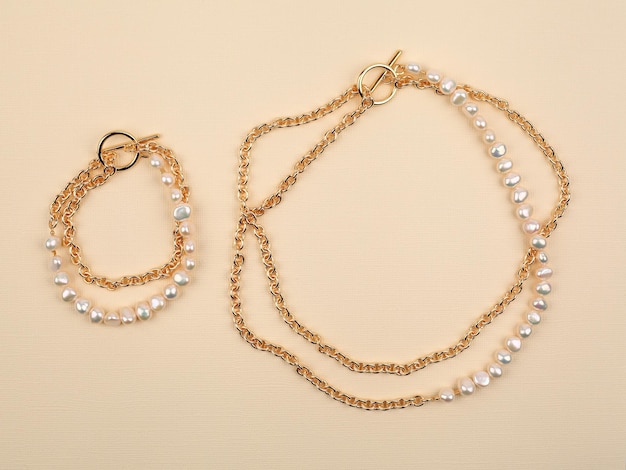 Elegante pulsera y collar de oro de perlas barrocas de lujo sobre fondo de textura beige. Fotografía de cerca