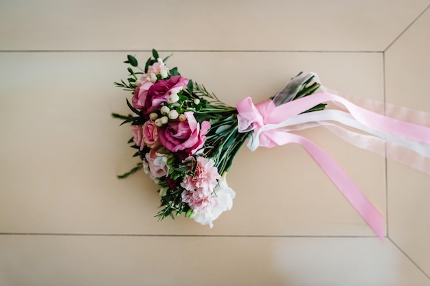 Elegante ramo de boda novia de rosas rosadas clavel blanco y flores verdes y verdes con cintas sobre una mesa pastel Cerrar decoración de boda Obra de arte plana vista superior