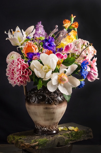 Elegante ramo de flores en un jarrón sobre un espacio negro en estilo oscuro, bodegón floral