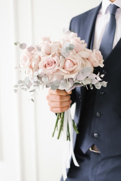 Foto elegante ramo de novia de delicadas rosas rosadas en manos del primer plano del novio