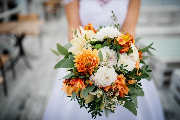 Elegante ramo de novia naranja y blanco en manos de la novia.