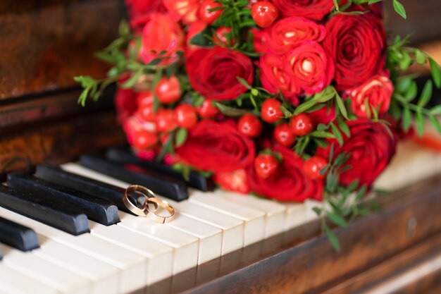 Elegante ramo de rosas rojas en el piano. detalles de boda.