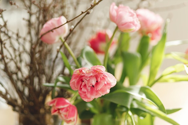 Elegante ramo de tulipanes y ramas de sauce en la mesa de madera de cerca Arreglo festivo floral en el comedor en la casa de campo Composición de flores de primavera Felices Pascuas