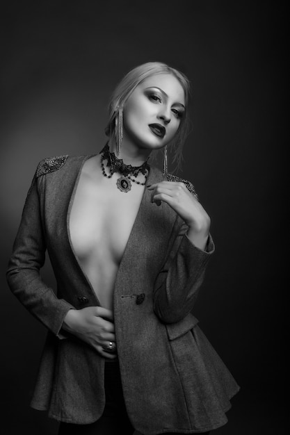 Elegante retrato de estudio en blanco y negro de una mujer magnífica con maquillaje brillante lleva chaqueta sobre un cuerpo desnudo