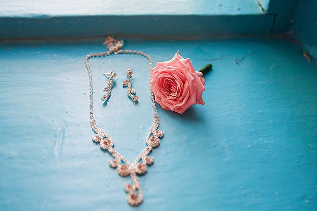 Elegante rosa con collar y aretes en azul