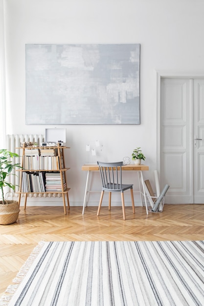 Elegante sala de estar escandinava con muebles de diseño, plantas, atril de bambú, escritorio de madera, cuadros de arte, parquet marrón en la decoración del hogar moderna